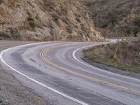 a man riding on the back of a white motorcycle down a curvy road