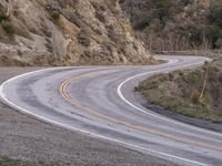 a man riding on the back of a white motorcycle down a curvy road