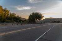 the motorcycle rider is riding down the winding country road at sunset by himself with motion blur