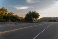 the motorcycle rider is riding down the winding country road at sunset by himself with motion blur