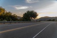 the motorcycle rider is riding down the winding country road at sunset by himself with motion blur