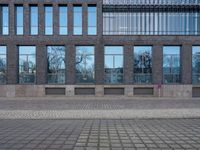 a person riding an electric skateboard across a brick walk way next to glass windows