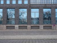 a person riding an electric skateboard across a brick walk way next to glass windows