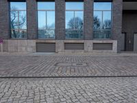 a person riding an electric skateboard across a brick walk way next to glass windows