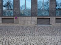 a person riding an electric skateboard across a brick walk way next to glass windows