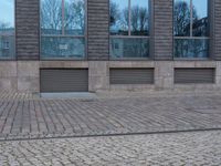 a person riding an electric skateboard across a brick walk way next to glass windows