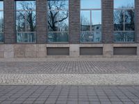 a person riding an electric skateboard across a brick walk way next to glass windows