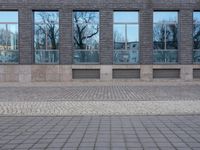 a person riding an electric skateboard across a brick walk way next to glass windows