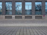 a person riding an electric skateboard across a brick walk way next to glass windows