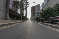 a photo taken while riding a motorcycle down a long road in the middle of city