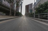 a photo taken while riding a motorcycle down a long road in the middle of city