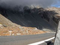 there is a man on a motorcycle riding down the road on the side of a mountain