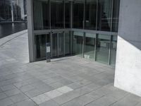 view of a walkway in front of the building and lake side water with a glass fronted building in the back