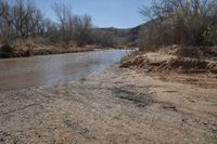 a small river next to the highway in the mountains where the road is flooded with water