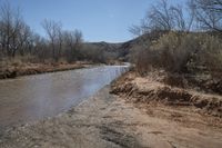 a small river next to the highway in the mountains where the road is flooded with water