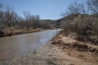 a small river next to the highway in the mountains where the road is flooded with water