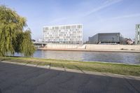 an image of a park bench next to the water side of a river, overlooking a bridge and buildings