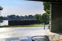 the view outside an open patio door overlooking a river and trees and a park area