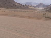 a person on a motorcycle rides in the desert toward the mountains, with a large valley below