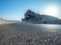 a very large hill near the sea and a rock formation on it's edge