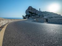 a very large hill near the sea and a rock formation on it's edge