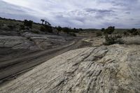 a lone desert road runs along the sides of a big rock formation in a dry arid landscape