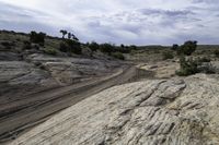 a lone desert road runs along the sides of a big rock formation in a dry arid landscape