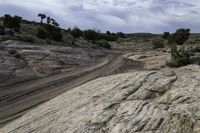 a lone desert road runs along the sides of a big rock formation in a dry arid landscape