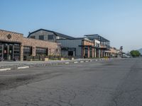 the empty street outside of the business district is empty and deserted with vehicles parked in it