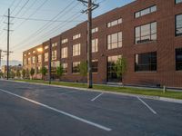 an empty street in front of a large red brick building on the other side of the road is a street light that has a line for motorists