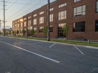 an empty street in front of a large red brick building on the other side of the road is a street light that has a line for motorists