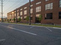 an empty street in front of a large red brick building on the other side of the road is a street light that has a line for motorists