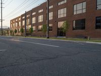 an empty street in front of a large red brick building on the other side of the road is a street light that has a line for motorists