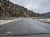 a road going across a bridge on a cloudy day in the mountains and over a large mountain