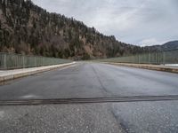 a road going across a bridge on a cloudy day in the mountains and over a large mountain