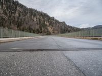 a road going across a bridge on a cloudy day in the mountains and over a large mountain