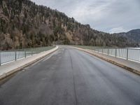 a road going across a bridge on a cloudy day in the mountains and over a large mountain