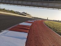 a road and a bridge over a hill on a clear day at sunrise with light reflected on the pavement