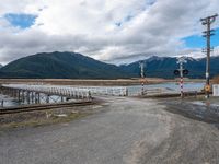 a bridge that is over the water on the road, with mountains in the background