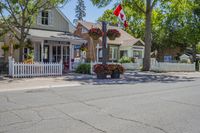 a road in a small residential area with houses and trees with a canadian flag flying over it