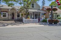 a road in a small residential area with houses and trees with a canadian flag flying over it
