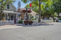 a road in a small residential area with houses and trees with a canadian flag flying over it
