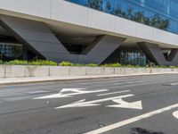 an office building with a large sidewalk and some white arrow signs on the asphalt of the road