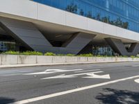 an office building with a large sidewalk and some white arrow signs on the asphalt of the road