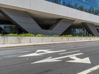 an office building with a large sidewalk and some white arrow signs on the asphalt of the road