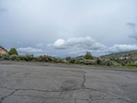 a mountain sits in the distance in a parking lot with a few trees and shrubbery