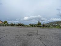 a mountain sits in the distance in a parking lot with a few trees and shrubbery