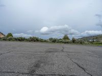 a mountain sits in the distance in a parking lot with a few trees and shrubbery