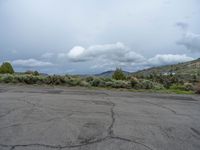 a mountain sits in the distance in a parking lot with a few trees and shrubbery