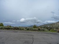 a mountain sits in the distance in a parking lot with a few trees and shrubbery